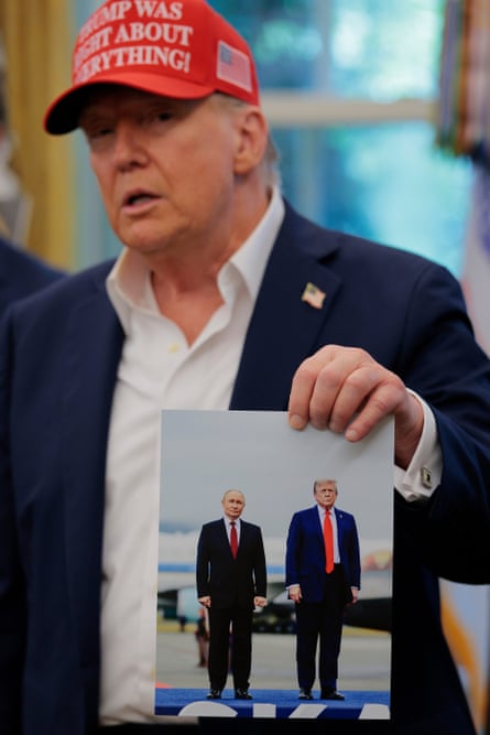 Donald Trump holds a photograph of him with Vladimir Putin in Alaska