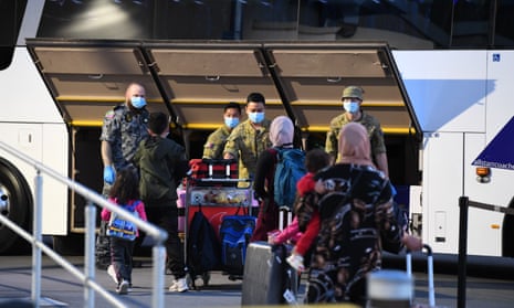 Passengers wearing facemasks arrive at Sydney airport and walk to board coaches which will take them into hotel quarantine