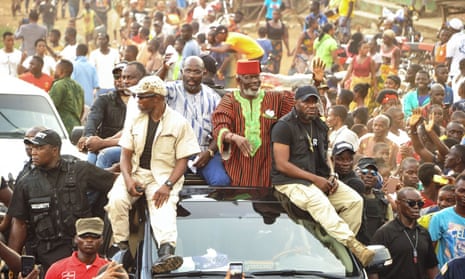 Former warlord Prince Johnson (centre right) waves to supporters on the top of a car with George Weah (centre left).