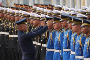 A Thai air force officer adjusts the cap of a member of an honour guard