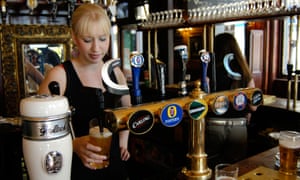 A bartender pours a pint of beer in a pub.