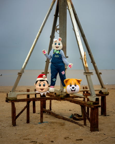 Someone wearing an Easter bunny costume, with two other ‘spare’ heads, one of a bear, the other wearing a red Sants hat, at his feet.