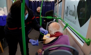 A firefighter administers a dose of the Pfizer/BioNTech Covid-19 vaccine to an elderly patient in the Vacci’Bus, a bus converted into a coronavirus disease consultation and vaccination centre.