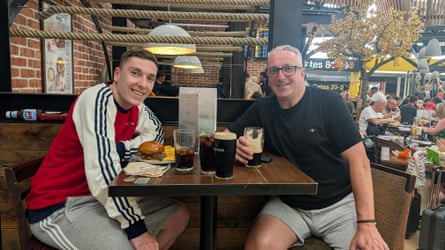 Kieran Regan and Darren Cornish sitting at a table with pints of Guinness in a beer garden