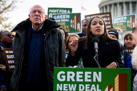 a woman speaks into a microphone with a placard affixed to it that reads ‘green new deal’