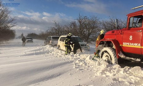 People push a car in the snow-hit Mykolaiv region