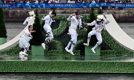 Four men in white outfits dance on a floating platform of artifical grass