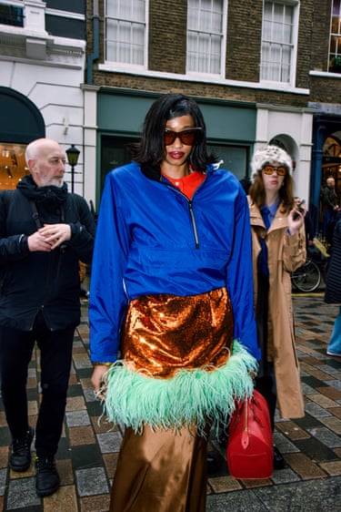 A person wearing a blue jacket and a gold skirt with feathers