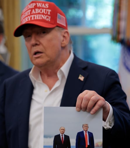 Donald Trump holds up a photograph Putin gave him in the White House on 22 August 2025.