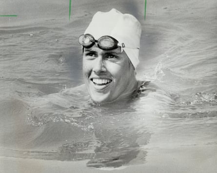 woman wearing goggles and swimming cap smiles while in water
