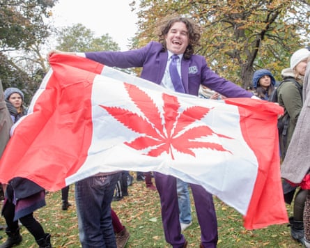 Man in purple suit hold red and white flag outside with trees behind