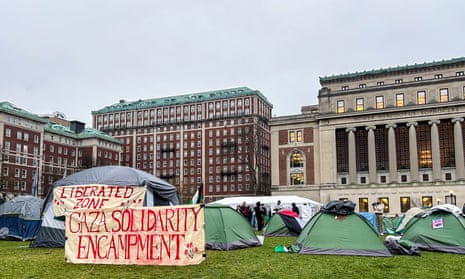 a row of tents with signs in a grassy area surrounded by brick and columned buildings