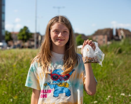 Girl smiling and holding up a plastic bag of cigarette butts