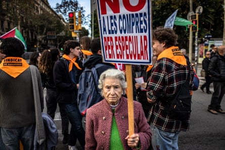 An elderly woman holds a placard and is surrounded by demonstrators in Barcelona