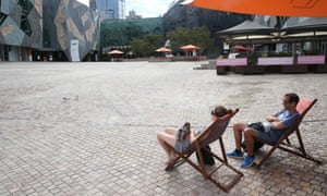 A couple relax under the sun at an empty Federation Square in Melbourne