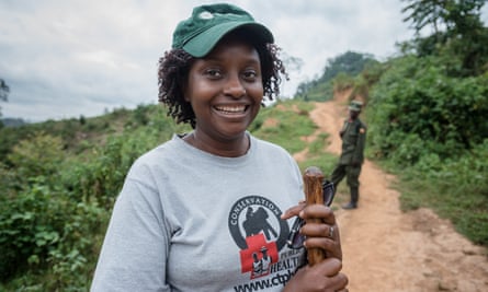 Gladys Kalema-Zikusoka in the hills of the Bwindi Impenetrable national park, behind her is a brown path that splits a landscape of green bushes.