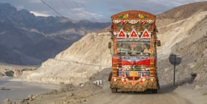 A large truck with bright paint drives through a desert