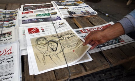 A man reaches out to take a copy of a newspaper with a drawing of two women on the front cover