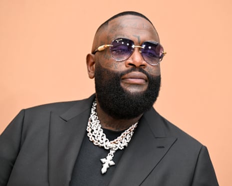 Rick Ross, bearded and in sunglasses, wears layered diamond chains with a cross pendant