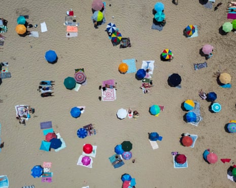 This aerial picture shows people sunbathing on Costa da Caparica beach in Almada, near Lisbon, during the first heatwave of the year.