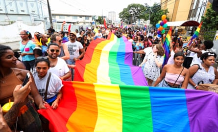 A crowd of people holding a rainbow flag.