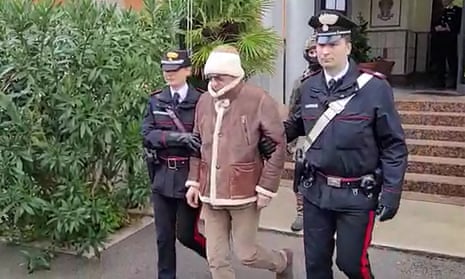 Carabinieri officers lead Matteo Messina Denaro out of clinic.
