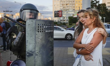 Two women talk with a riot police officer as police block a part of a street in the capital Minsk.