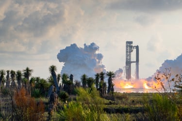 A Starship rocket launches amid smoke and flames