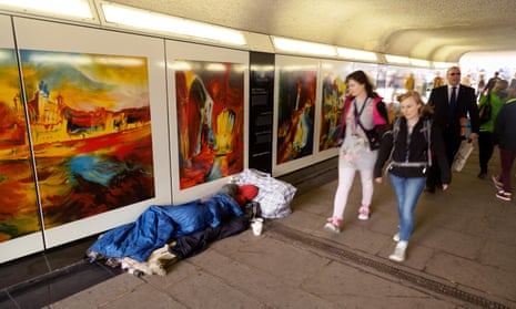 People walking past a homeless person sleeping on the street in Tower Hill, London.