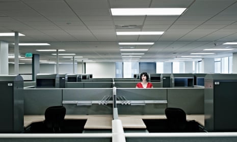 Businesswoman standing alone in empty officeBusinesswoman standing alone at cubicle in empty office