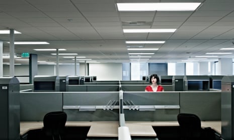 Posed photo of a woman sitting alone in a large open plan office