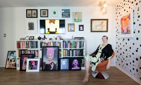 Arabella Proffer, who is living with cancer, sitting in ana orange chair in front of a bookshelf and a wall full of portraits