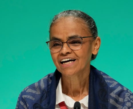 Marina Silva smiling in front of a green background