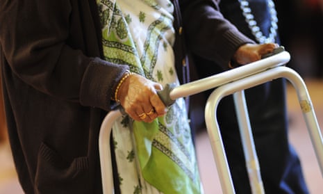 A woman is helped to her chair in a care home.