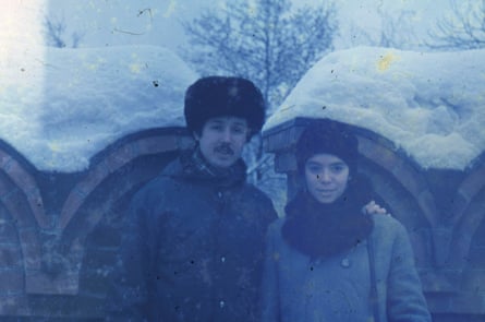 A Cuban couple who live in the USSR visit Armenia in 1984, in Soviet-style fur hats, snow on the buildings behind them