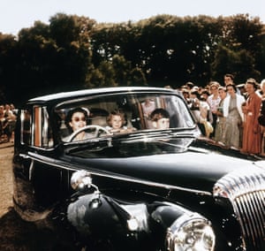 1957: Queen Elizabeth II driving her children Prince Charles and Princess Anne at Windsor, watched by a group of onlookers