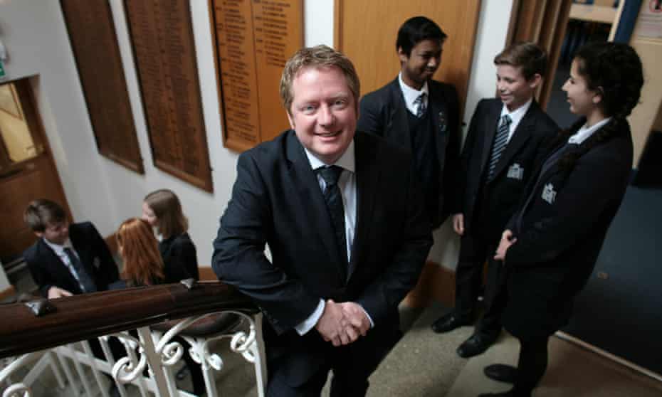 Shaun Fenton on staircase with pupils in background