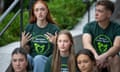 A group of teenagers wearing green 'Newtown Action Alliance' T-shirts sit on the ground and talk.