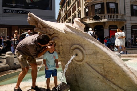 A man helps a child cool off with water from the Barcaccia Fountain at the foot of the Spanish Steps during a heatwave in Rome, Italy.