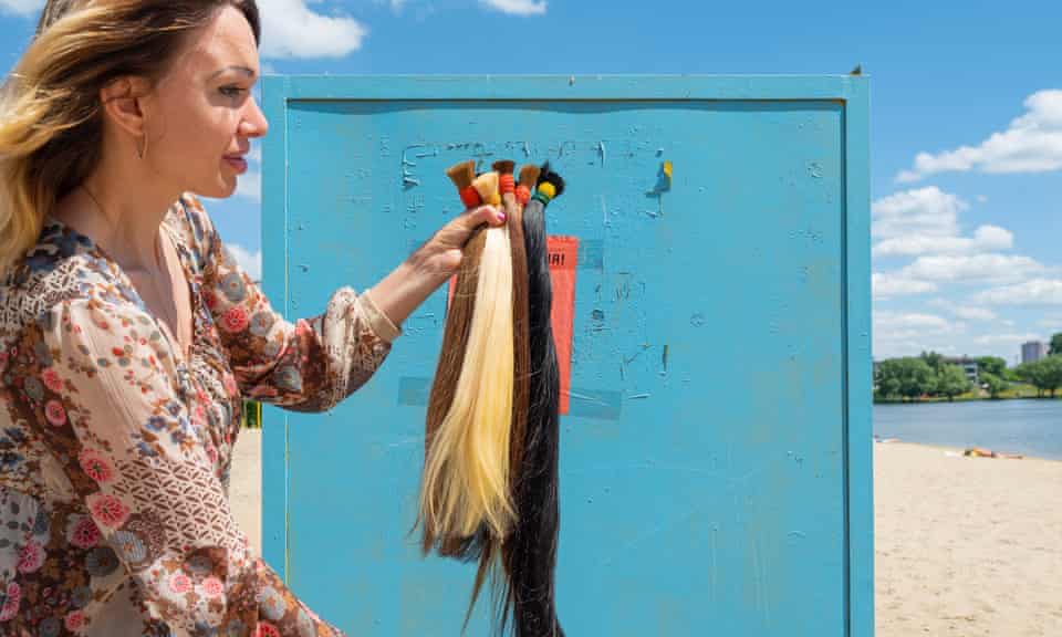 Tatiana 34, holding up several ponytails of hair in different colours that she has cut off.