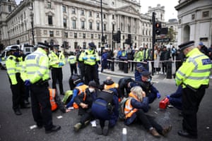 Insulate Britain activists have their hands glued to the tarmac as they block a road outside the Houses of Parliament during a protest in London.