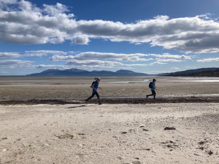 Two figures running on wild deserted beach