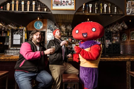 Melbourne game developer David Ashby and comedian Broden Kelly with Pro Jank Footy mascot Mr Footy.