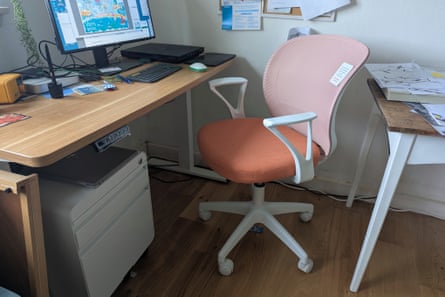 A working from home setup with a desk, computer and a pink and orange desk chair