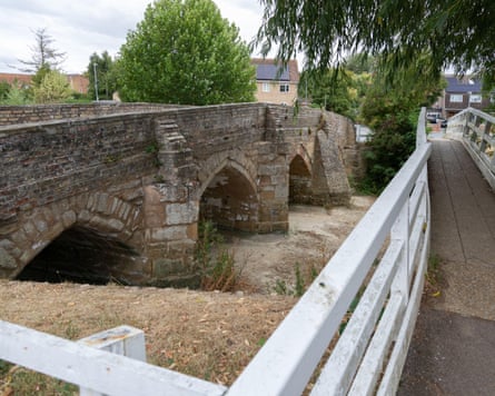 A stone bridge and newer footbridge over a dried-up brook