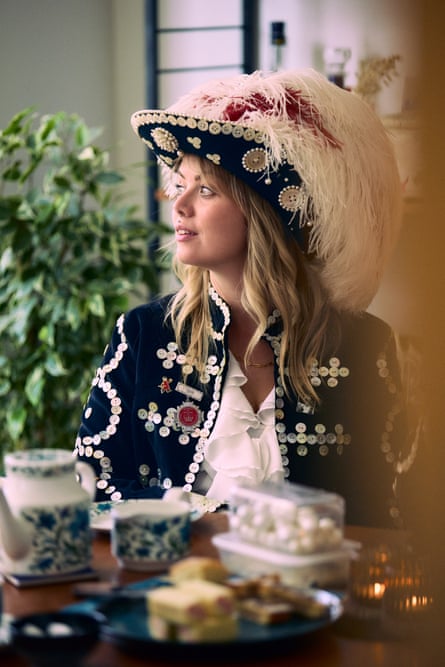 Ashleigh-Rose Harman in her pearly outfit sat at a dining table in her kitchen with tea and biscuits on the table in front of her