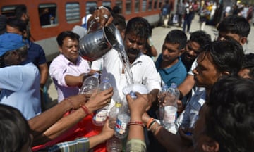 A volunteer distributes drinking water to train passengers on a hot summer day at the Jalandhar Cantonment railway station in Jalandhar