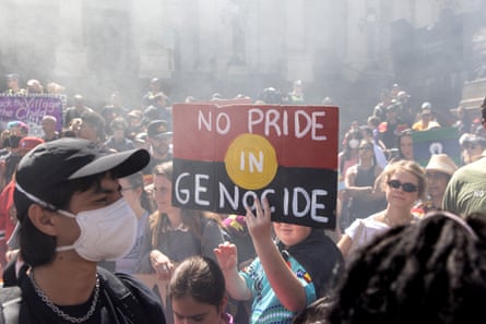 A protester holding a placard that reads ‘No Pride In Genocide’ inside a crowd with smoke filling the air