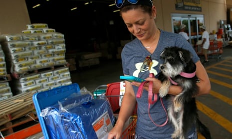 Michelle Smith checks her smart phone for news while clutching her dog Sophia as she leaves a Home Depot store with storm preparation supplies in Tampa.