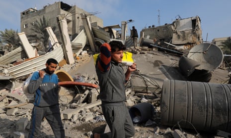 Palestinians walk past debris at the site of Israeli strikes on homes in Khan Younis